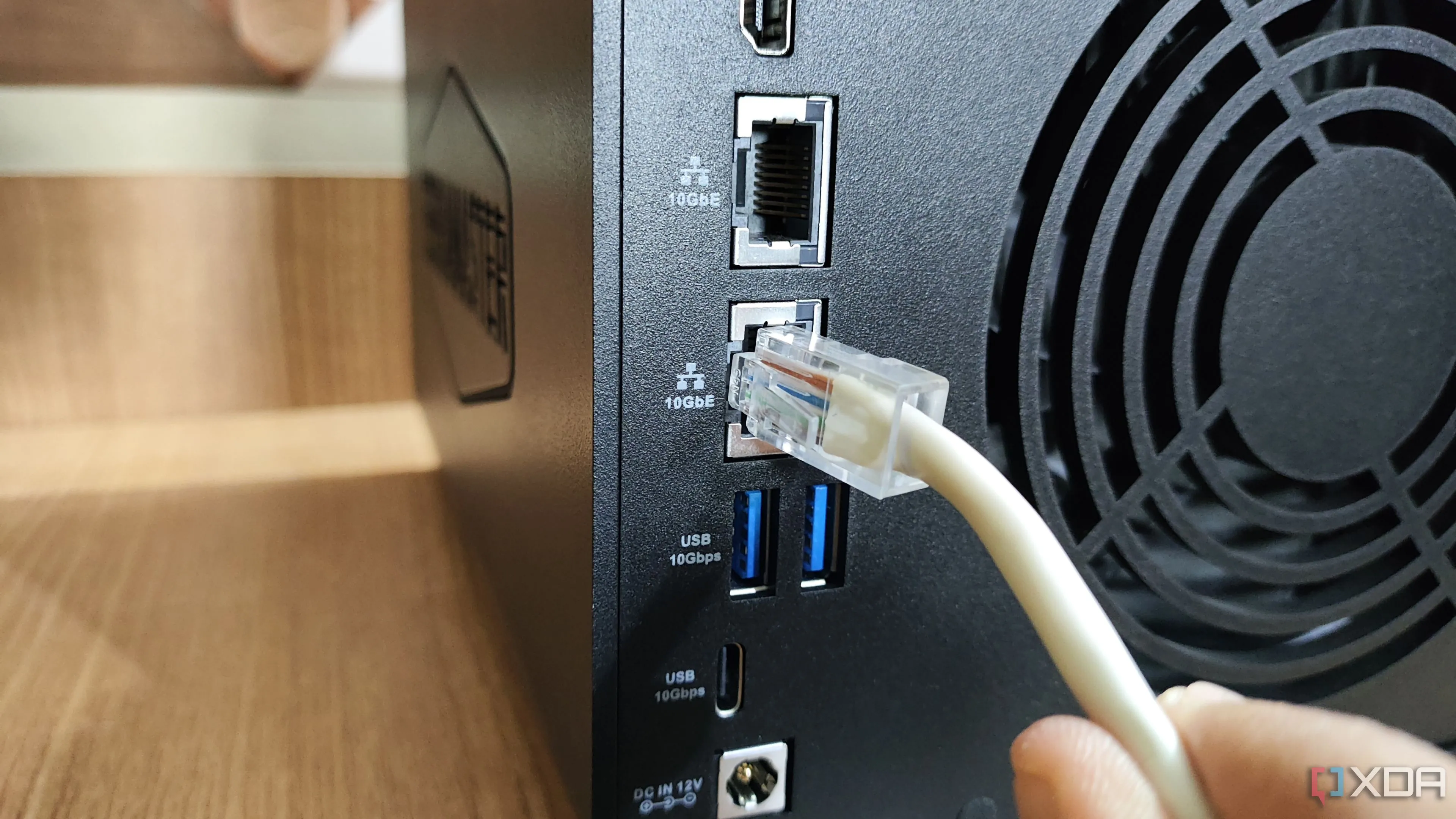 Cắm cáp Ethernet vào cổng mạng của thiết bị NAS, tượng trưng cho kết nối và hoạt động của hệ thống lưu trữ tại nhà