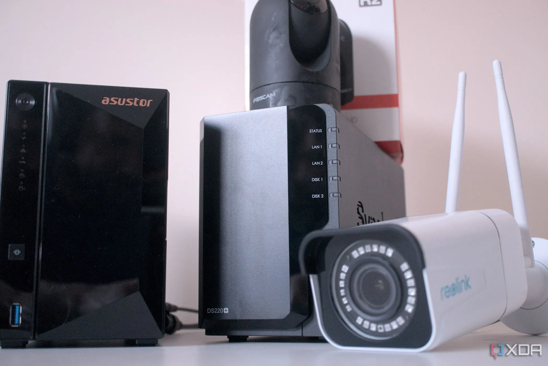 Tay người đặt ổ cứng HDD vào khay ổ của hệ thống NAS, phía sau là camera an ninh, minh họa việc sử dụng HDD cho lưu trữ giám sát.