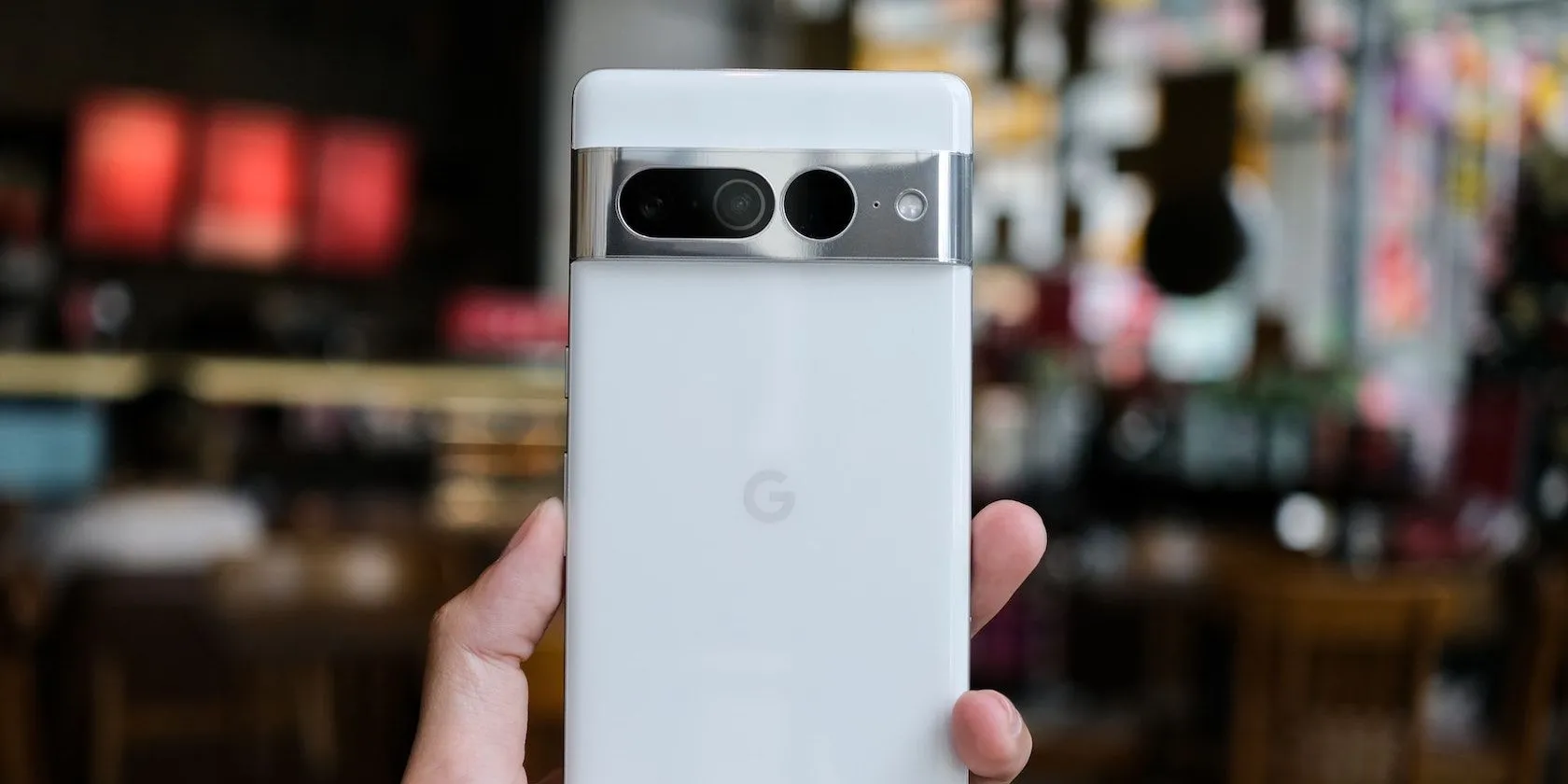 Điện thoại Google Pixel 7 Pro đang được cầm trên tay, minh họa tính năng sạc không dây ngược (Wireless Power Sharing) để nạp năng lượng cho thiết bị khác.