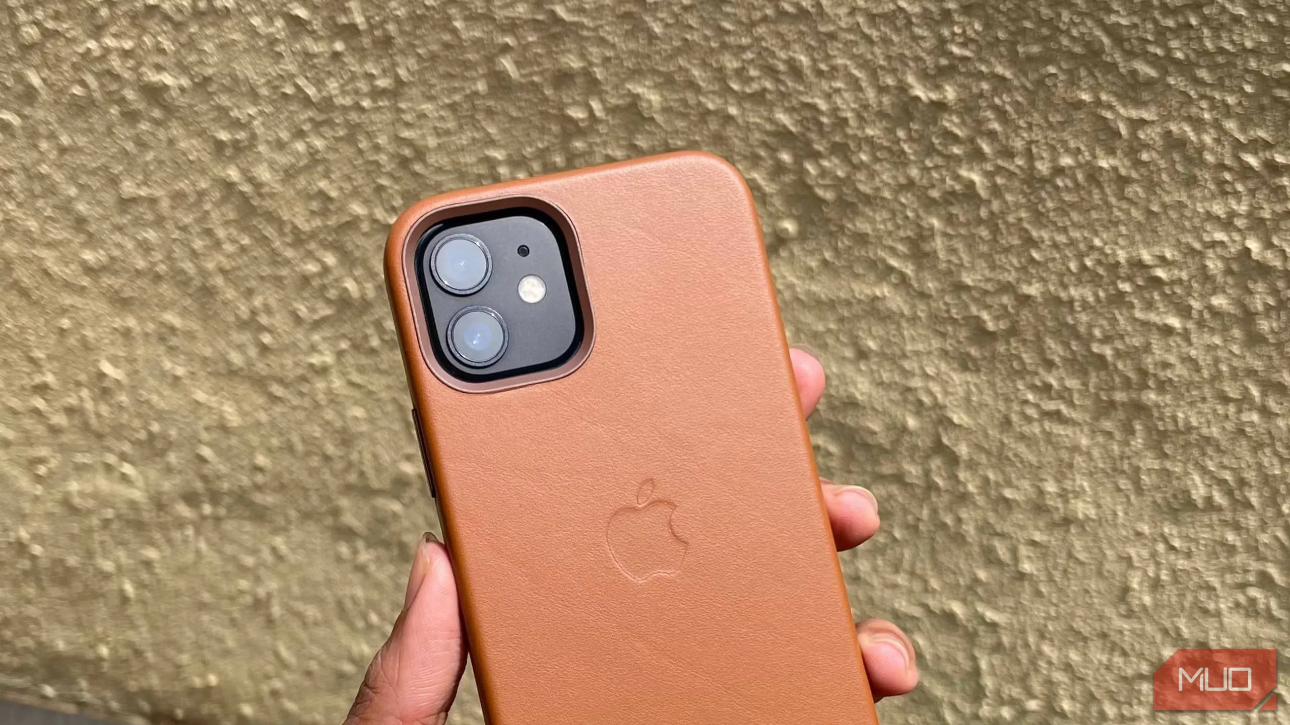 Ốp lưng da iPhone 12 màu nâu được cầm trên tay, thể hiện sự sang trọng và bền bỉ của vật liệu da truyền thống.