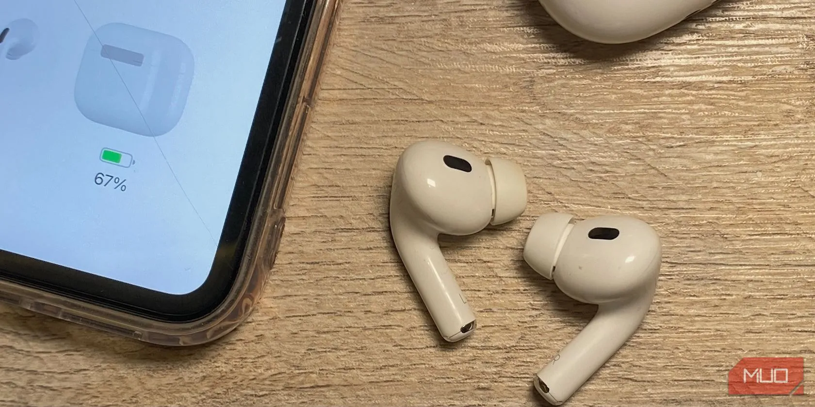 AirPods màu trắng đặt trên bàn gỗ cạnh một chiếc iPhone