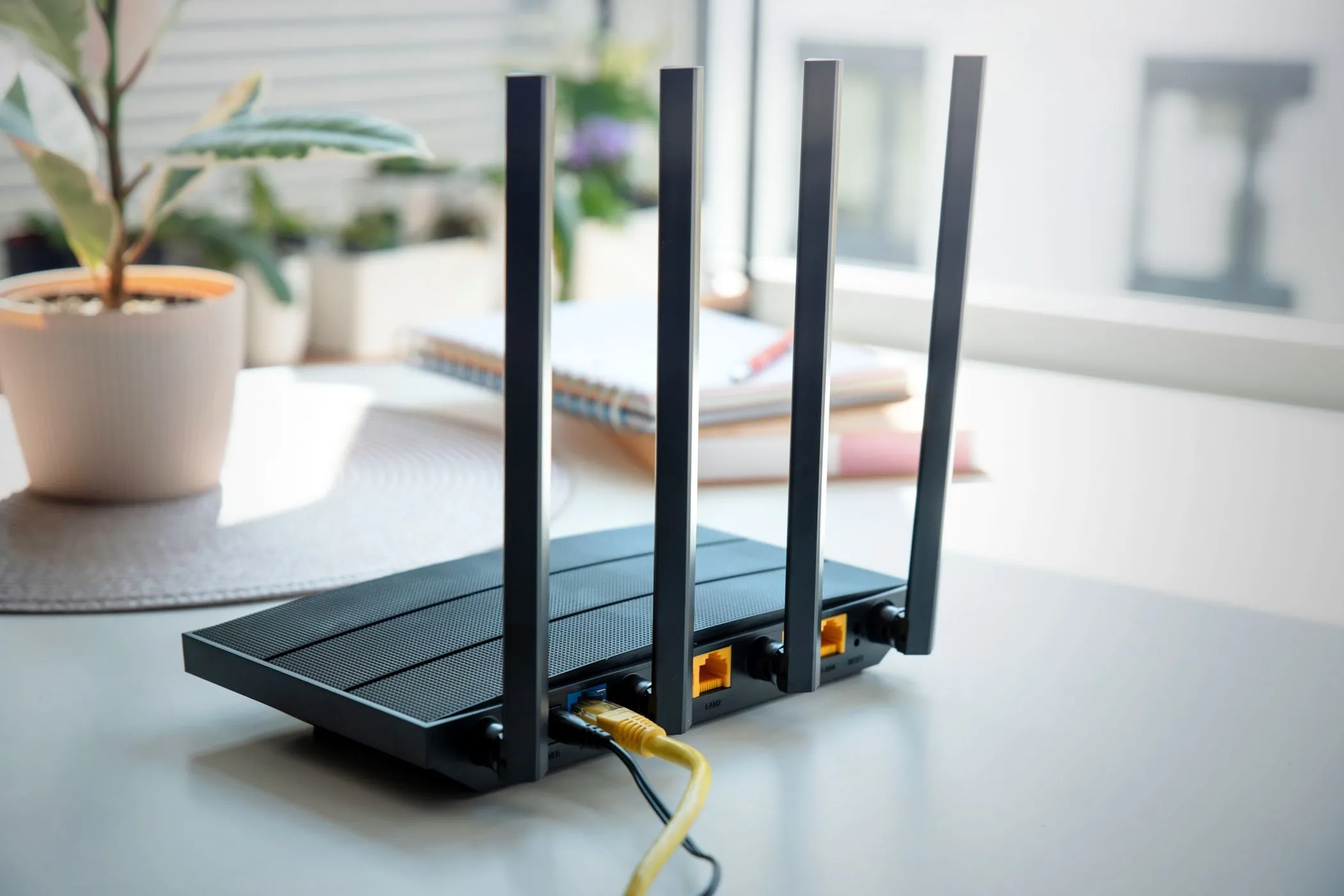 Bộ định tuyến Wi-Fi hiện đại với bốn ăng-ten trên bàn gỗ sáng, biểu tượng của kết nối internet gia đình an toàn.