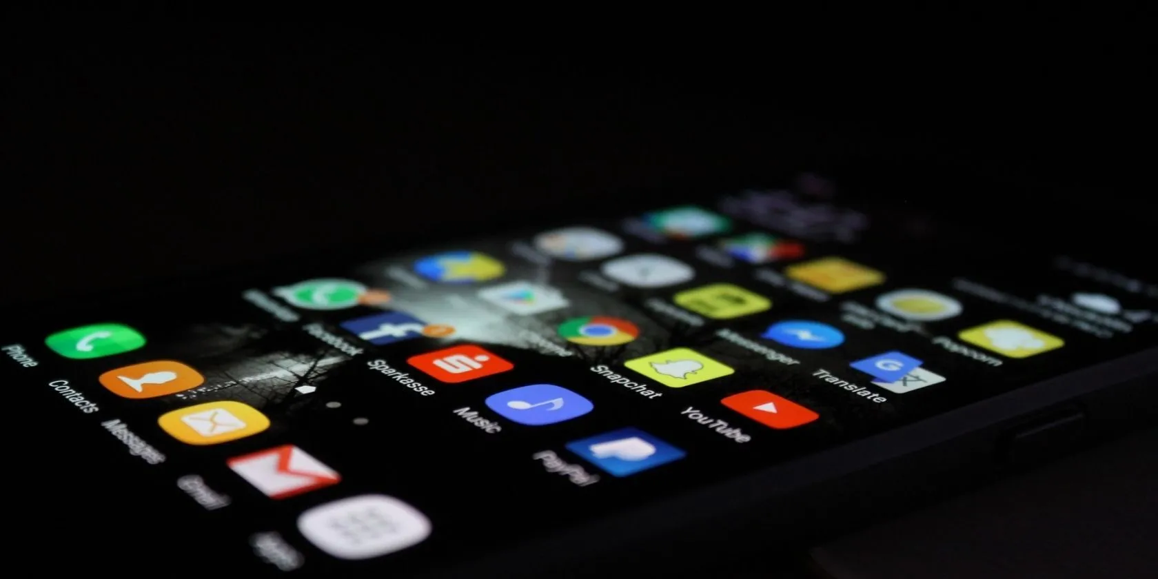 Điện thoại iPhone màu đen hiển thị màn hình chính với nhiều ứng dụng