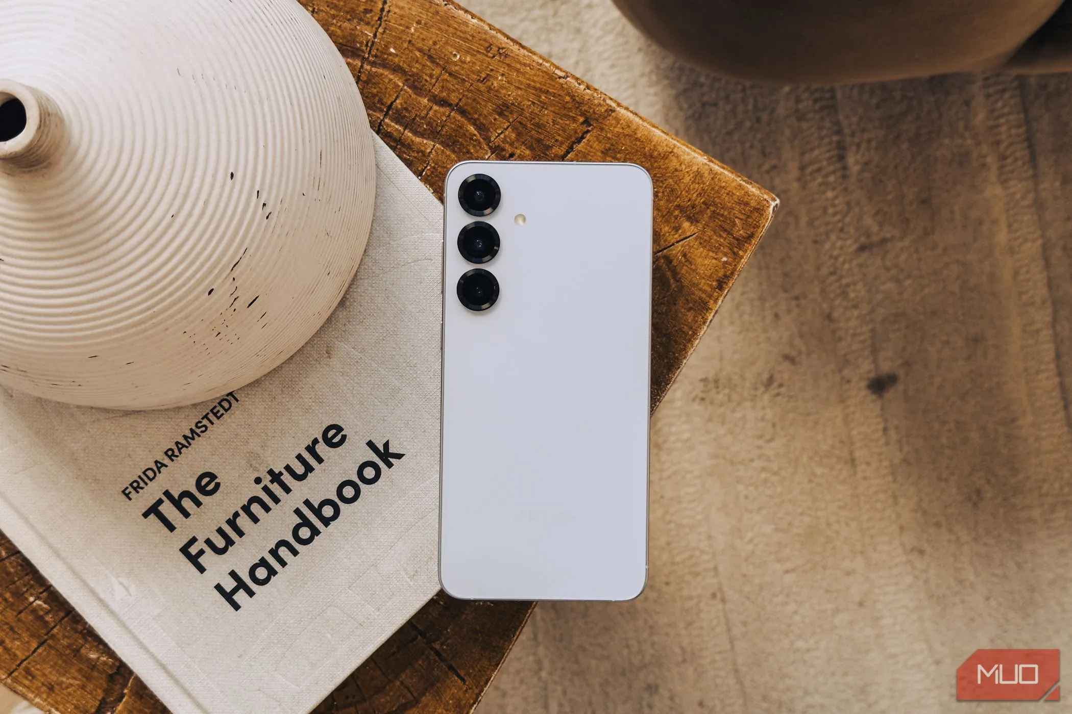 Điện thoại Samsung Galaxy S25 màu bạc đặt trên sách trắng, minh họa thiết kế camera