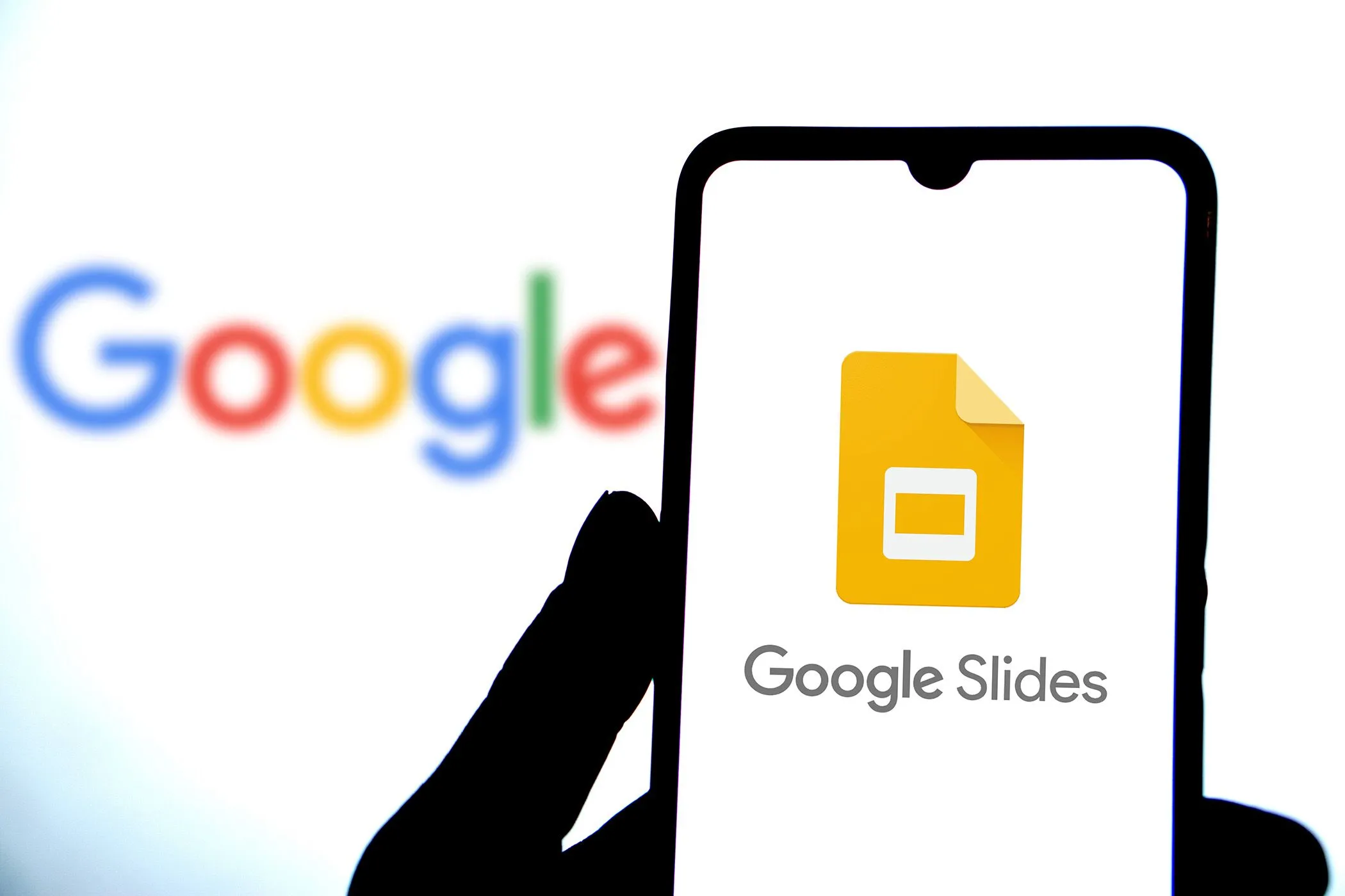 Hình ảnh ứng dụng Google Slides đang chạy trên điện thoại thông minh, với logo Google nổi bật phía sau.
