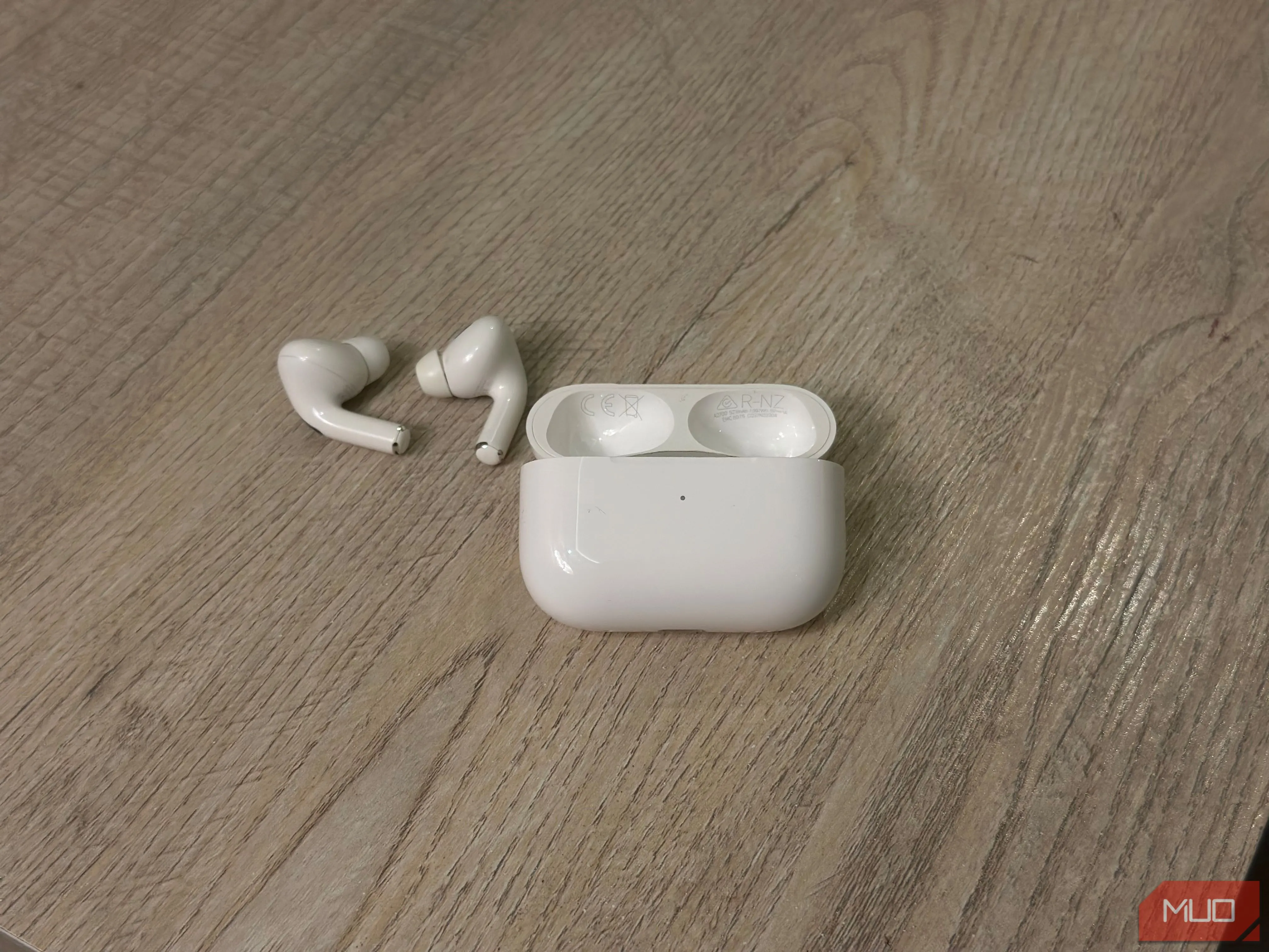 Hộp sạc AirPods và các tai nghe đặt trên bàn, hiển thị số model và serial ở mặt trong nắp