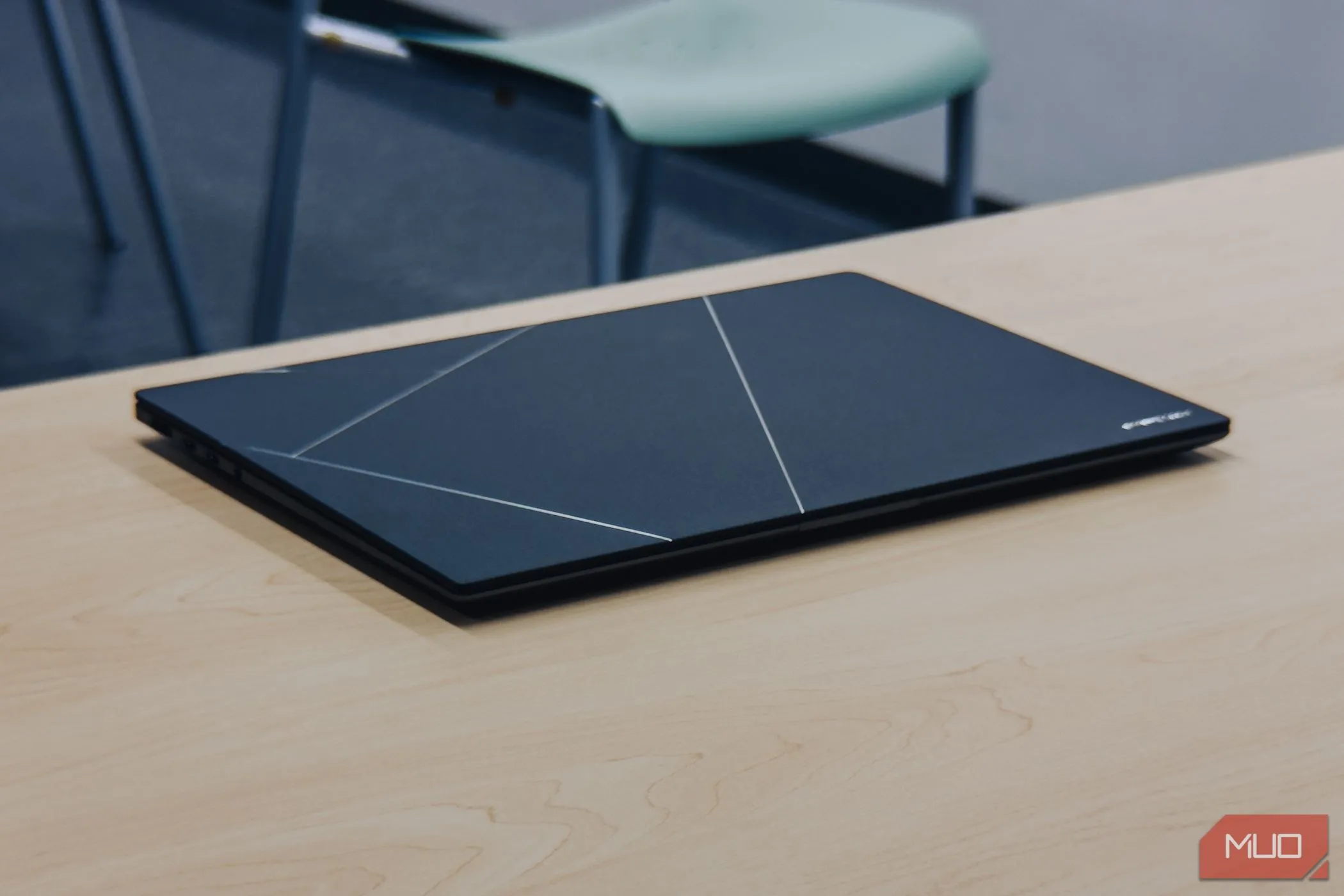 Laptop ASUS Zenbook S 16 OLED màu trắng khi gập lại trên bàn gỗ