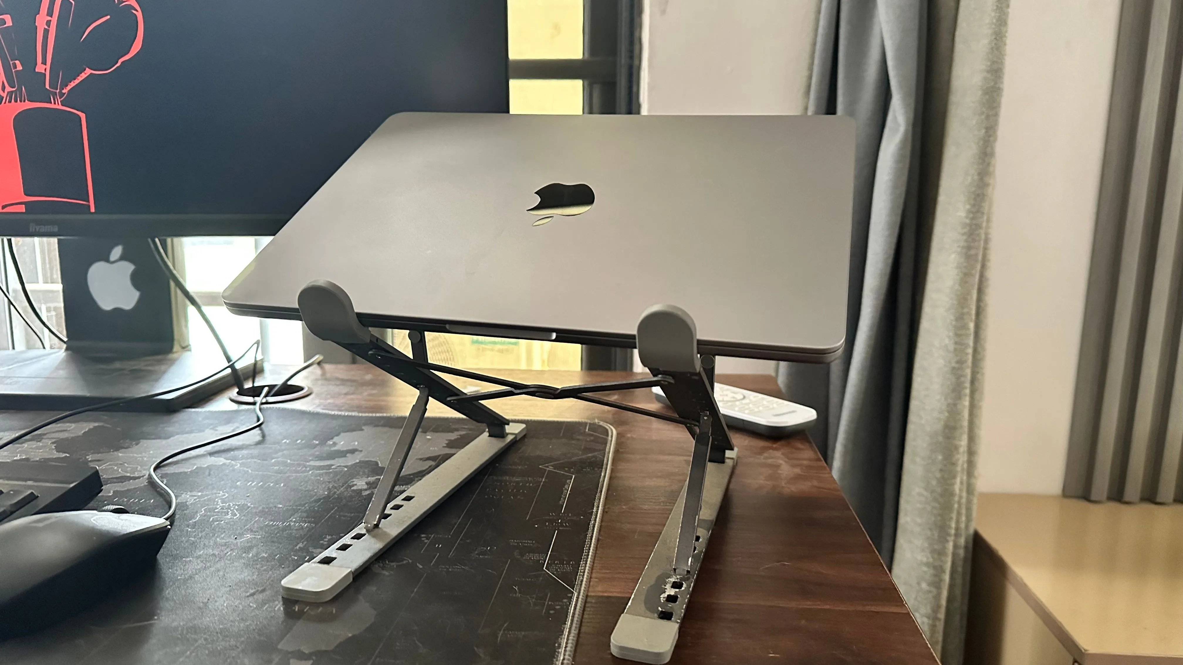 MacBook đặt trên đế tản nhiệt cạnh màn hình ngoài, minh họa cách tản nhiệt tốt hơn giúp bảo vệ tuổi thọ pin laptop.