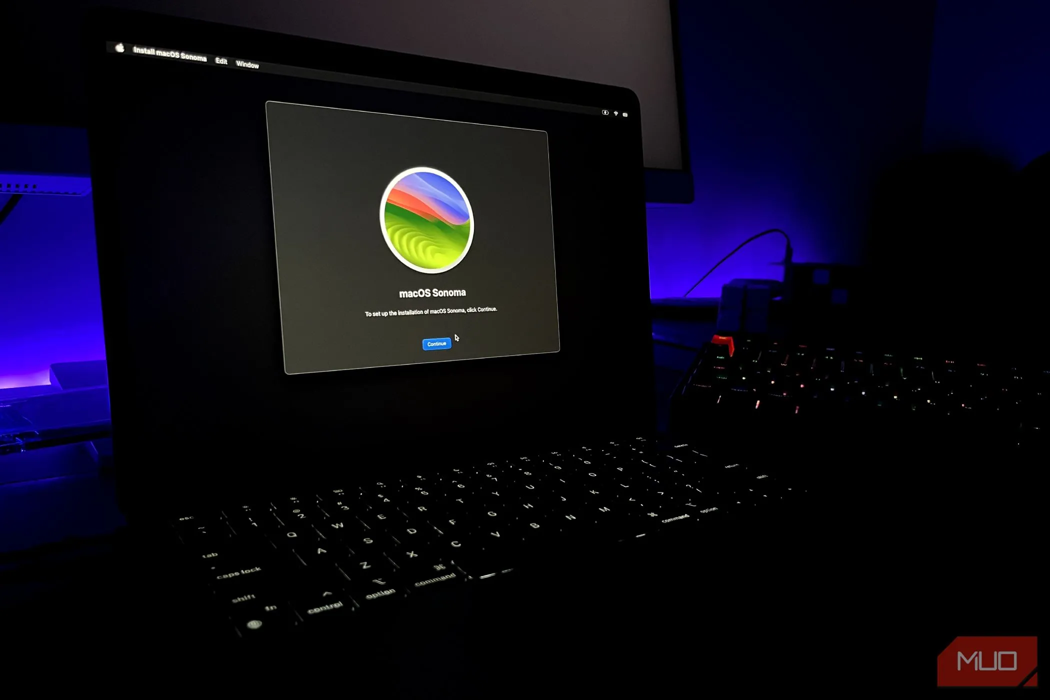 Màn hình cài đặt macOS Sonoma trên MacBook Air với bàn phím ở hậu cảnh