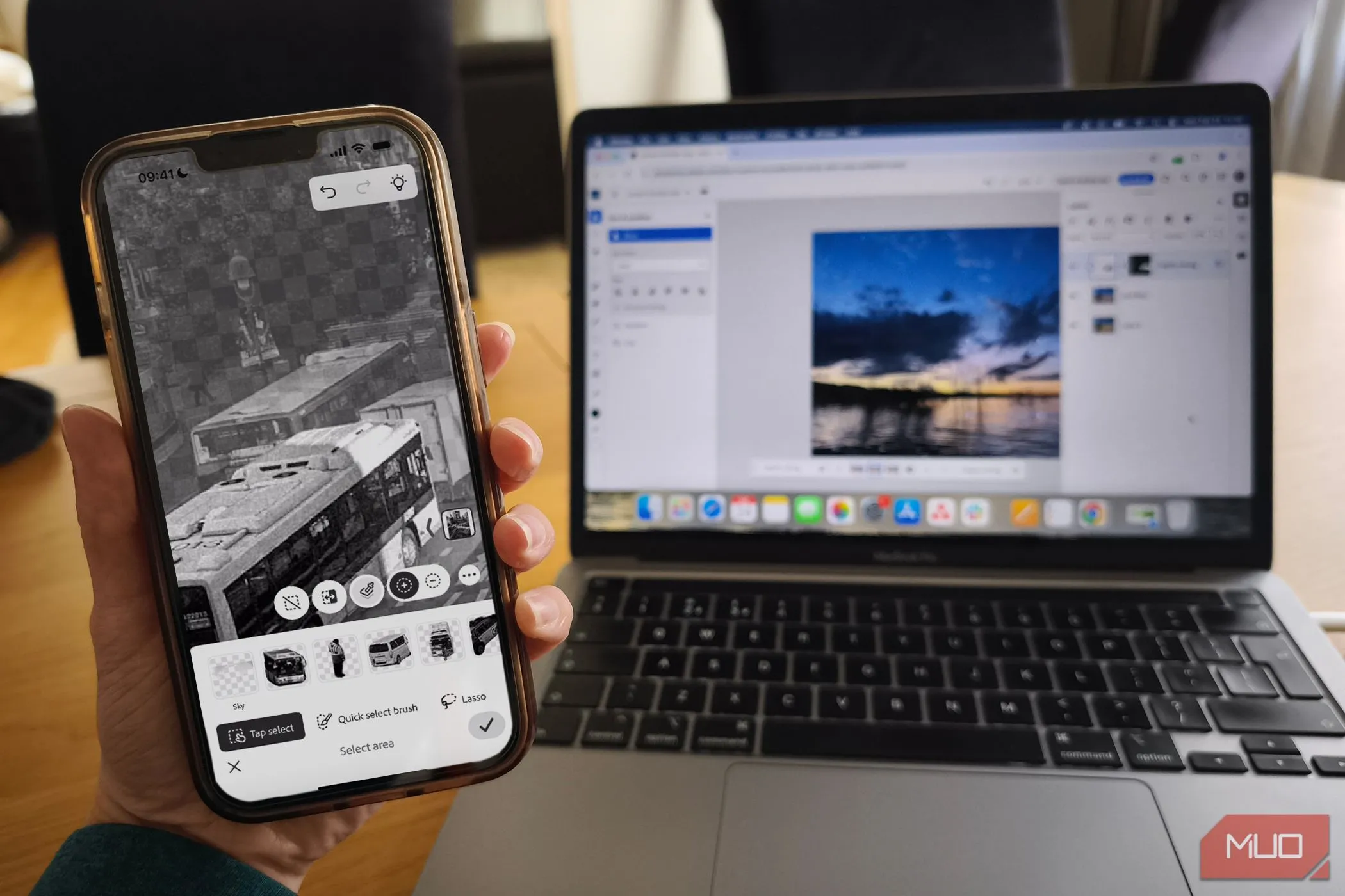 Minh họa sự đồng bộ liền mạch giữa ứng dụng Photoshop Mobile trên điện thoại và Photoshop trên nền web, cùng với việc chỉnh sửa trên MacBook, làm nổi bật hệ sinh thái Adobe.