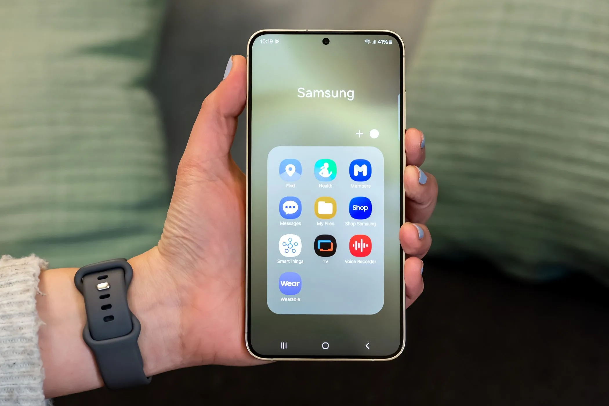 Một chiếc điện thoại Samsung hiển thị giao diện One UI với nhiều ứng dụng Samsung cài sẵn trong một thư mục, minh họa vấn đề bloatware và ứng dụng rác.