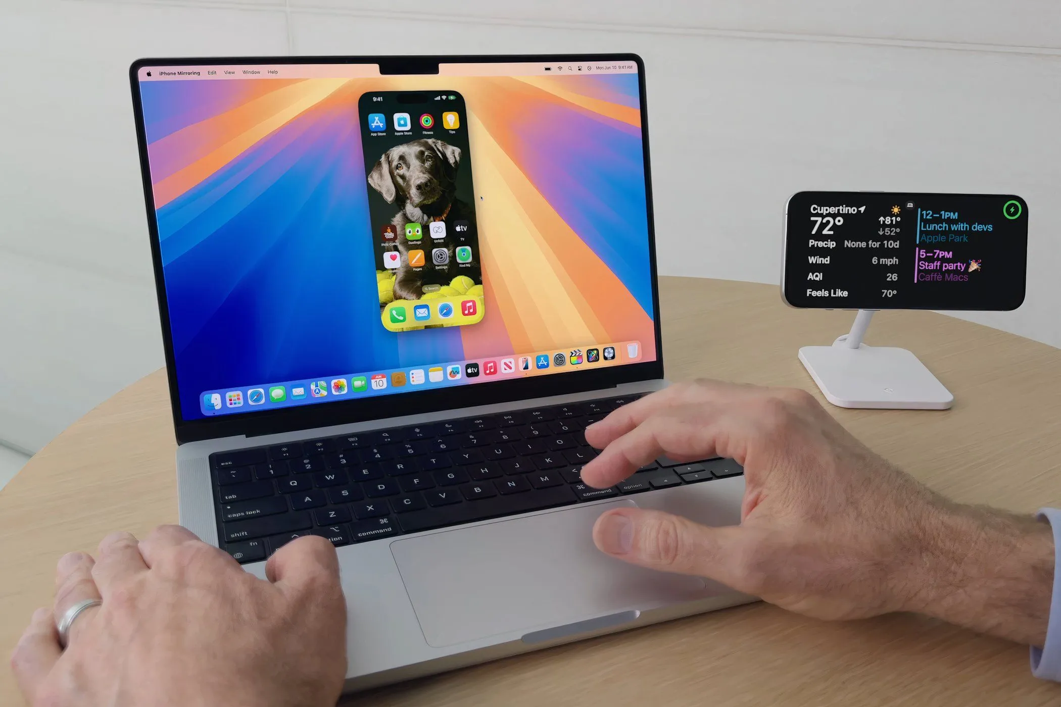 Một người đàn ông đang sử dụng MacBook Pro chạy macOS Sequoia với tính năng iPhone Mirroring để điều khiển iPhone từ máy Mac
