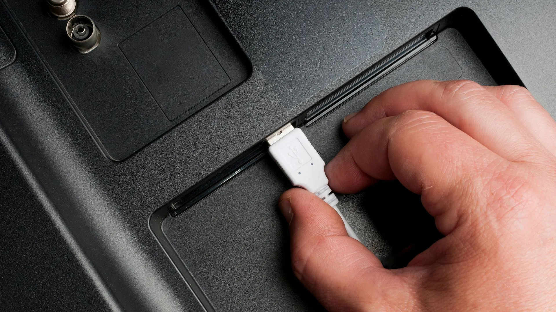 Người dùng cắm cáp USB Type-A vào cổng phía sau TV, minh họa việc cắm sạc không đúng đầu ra có thể gây hại thiết bị