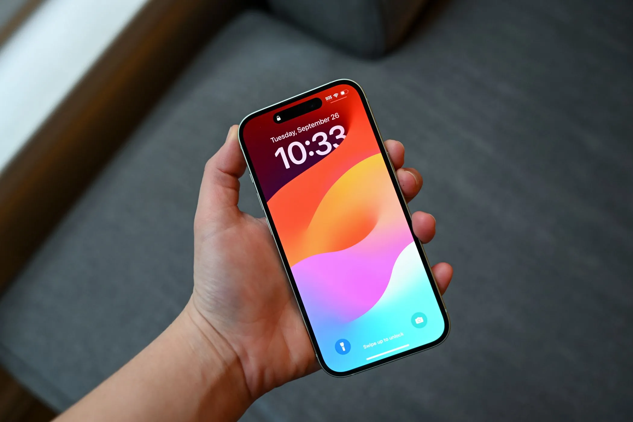 Người dùng cầm iPhone 15 đã dán miếng bảo vệ riêng tư giúp che đi vết xước nhỏ trên màn hình