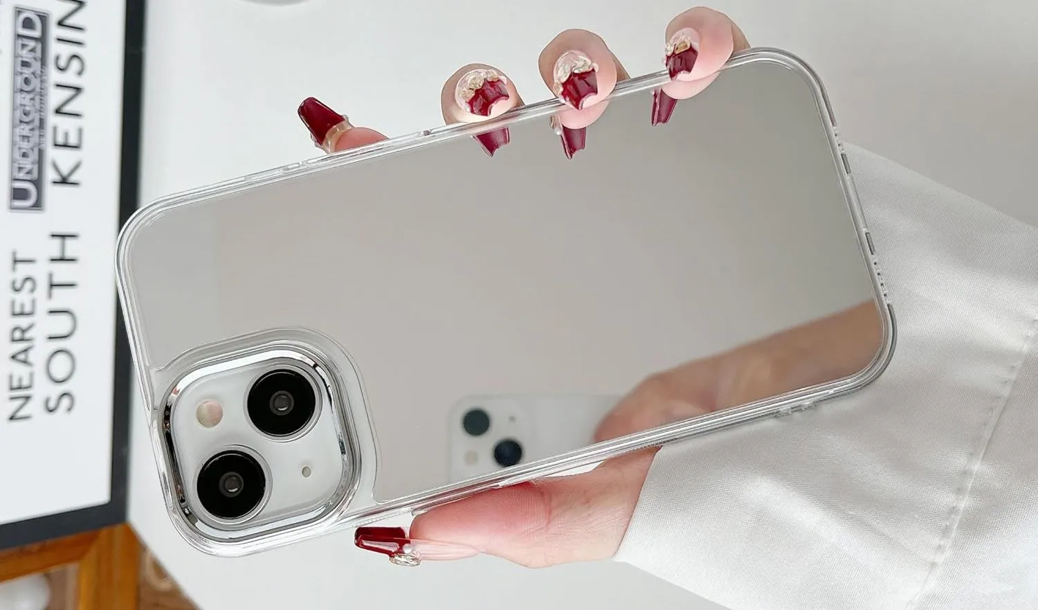 Người dùng cầm iPhone với ốp lưng có mặt gương phản chiếu, biến mặt lưng điện thoại thành công cụ kiểm tra nhanh.