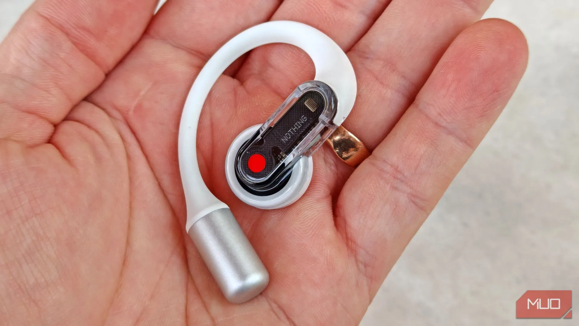 Người dùng cầm tai nghe Nothing Ear (open) bên phải trên tay, hiển thị chi tiết phần thân và loa của tai nghe.
