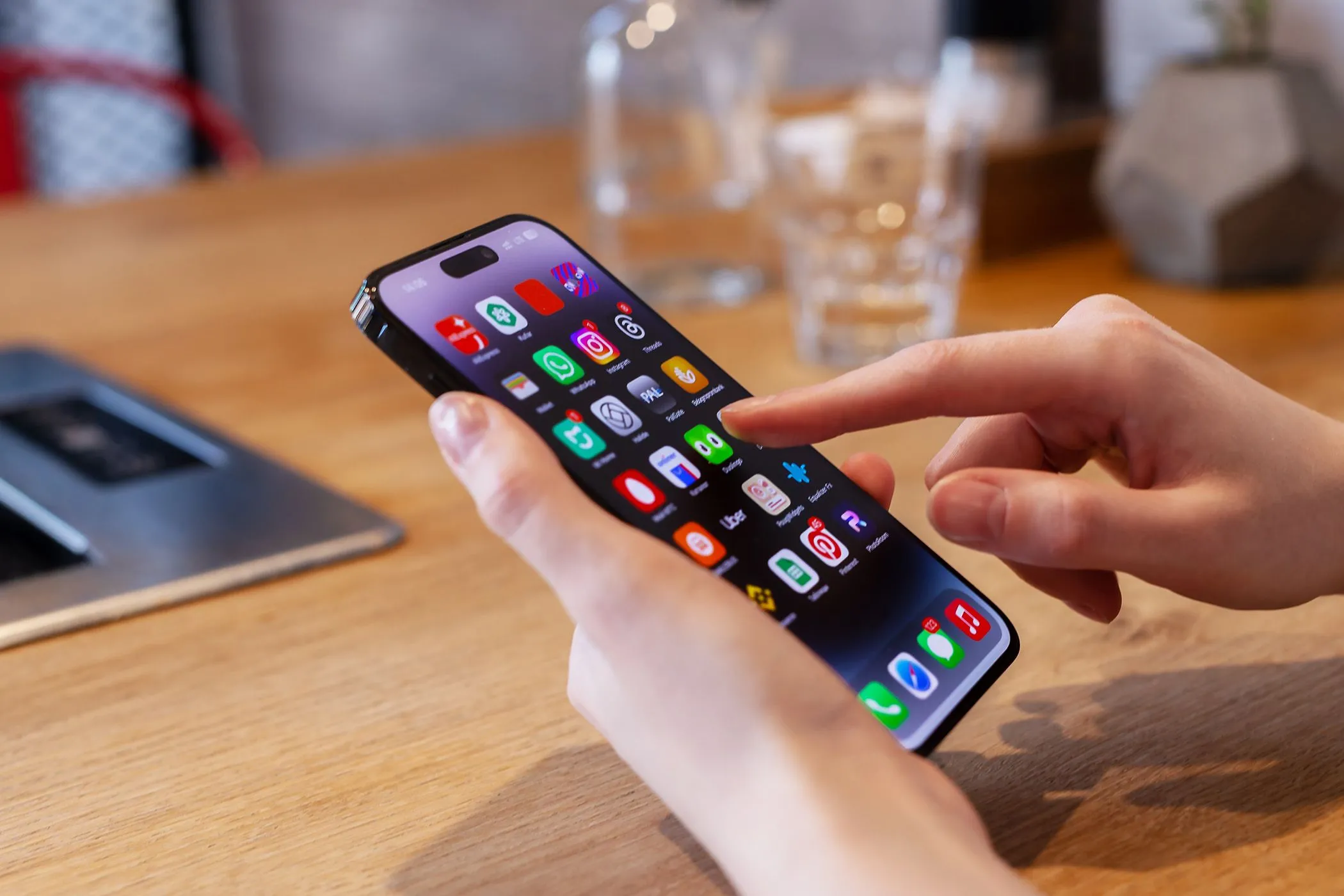 Người dùng đang thao tác trên chiếc iPhone đặt trên bàn, thể hiện sự cần thiết của tính năng lưu nguồn ảnh chụp màn hình để nâng cao trải nghiệm