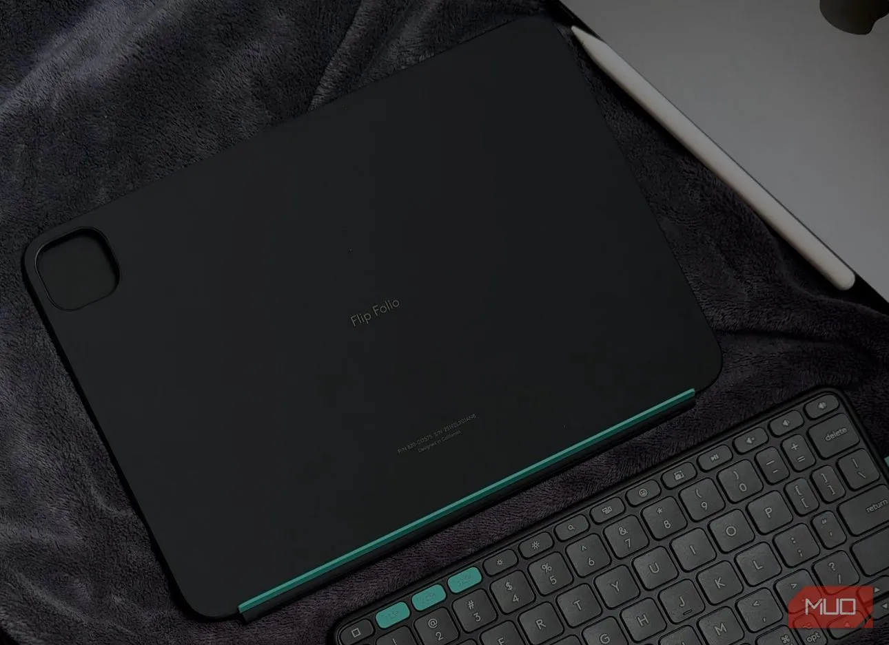 Ốp bảo vệ Logitech Flip Folio và bàn phím rời đặt trên chăn cạnh iPad, minh họa khả năng sử dụng linh hoạt và tách rời của bàn phím iPad này.